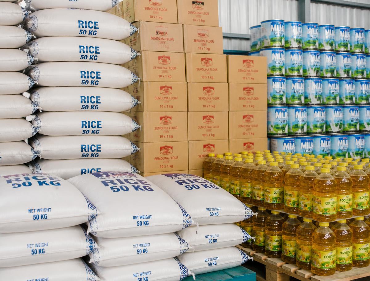 Stacked staples: rice bags, semovita cartons, milk tins and cooking oil